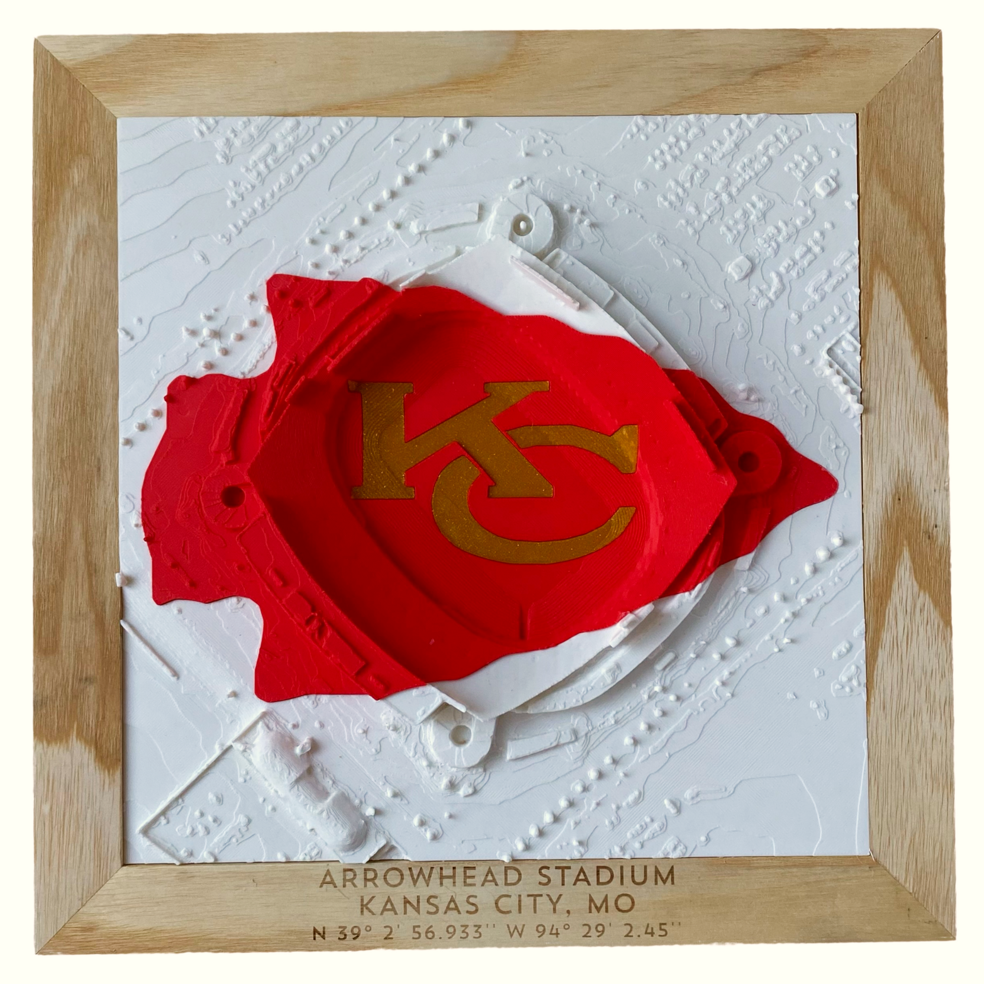 White 3D rendering of Arrowhead Stadium with red and gold KC Arrowhead logo inlay in a wooden frame