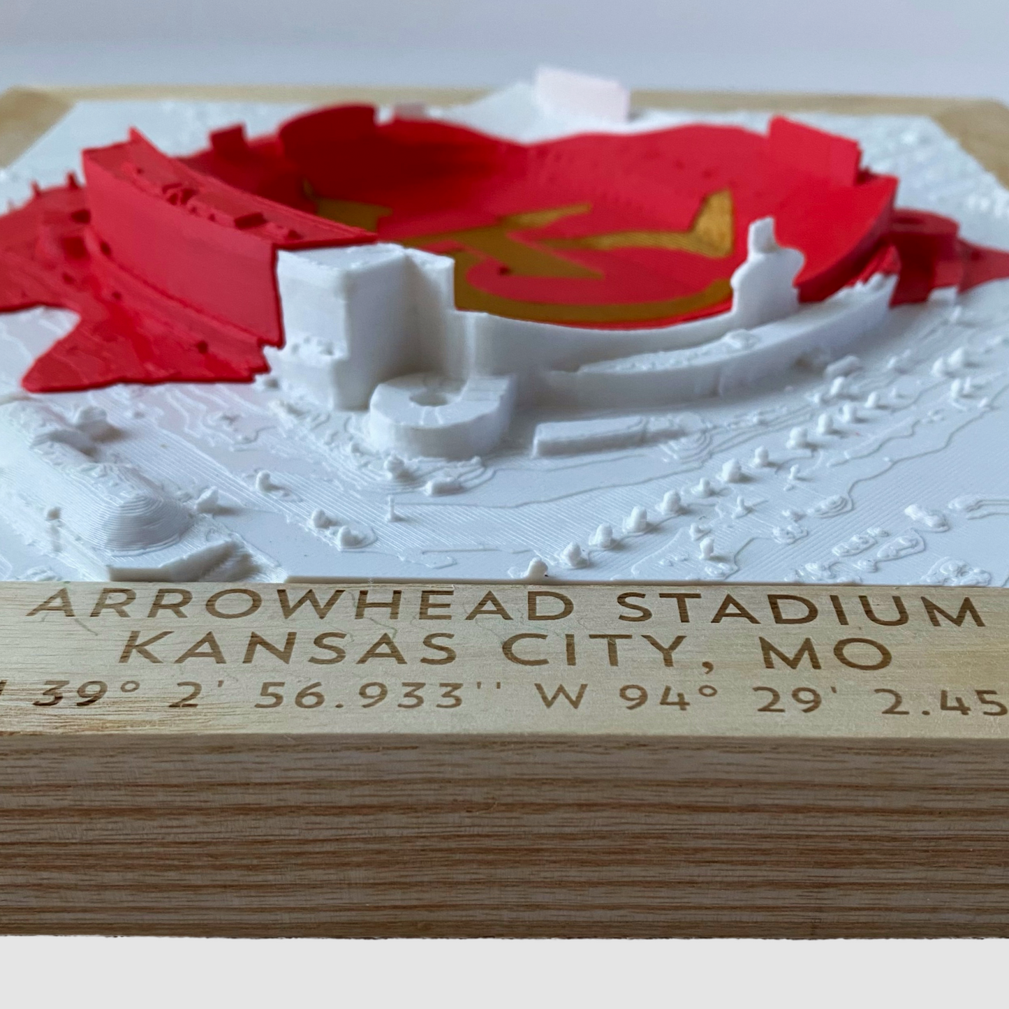 White 3D rendering of Arrowhead Stadium with red and gold KC Arrowhead logo inlay in a wooden frame