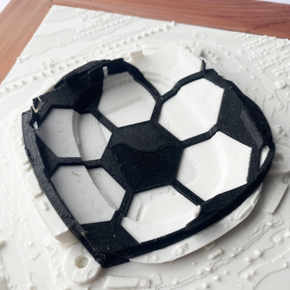 Framed 3D rendering of Arrowhead Stadium with heart-shaped black and white inlay in a soccer ball design