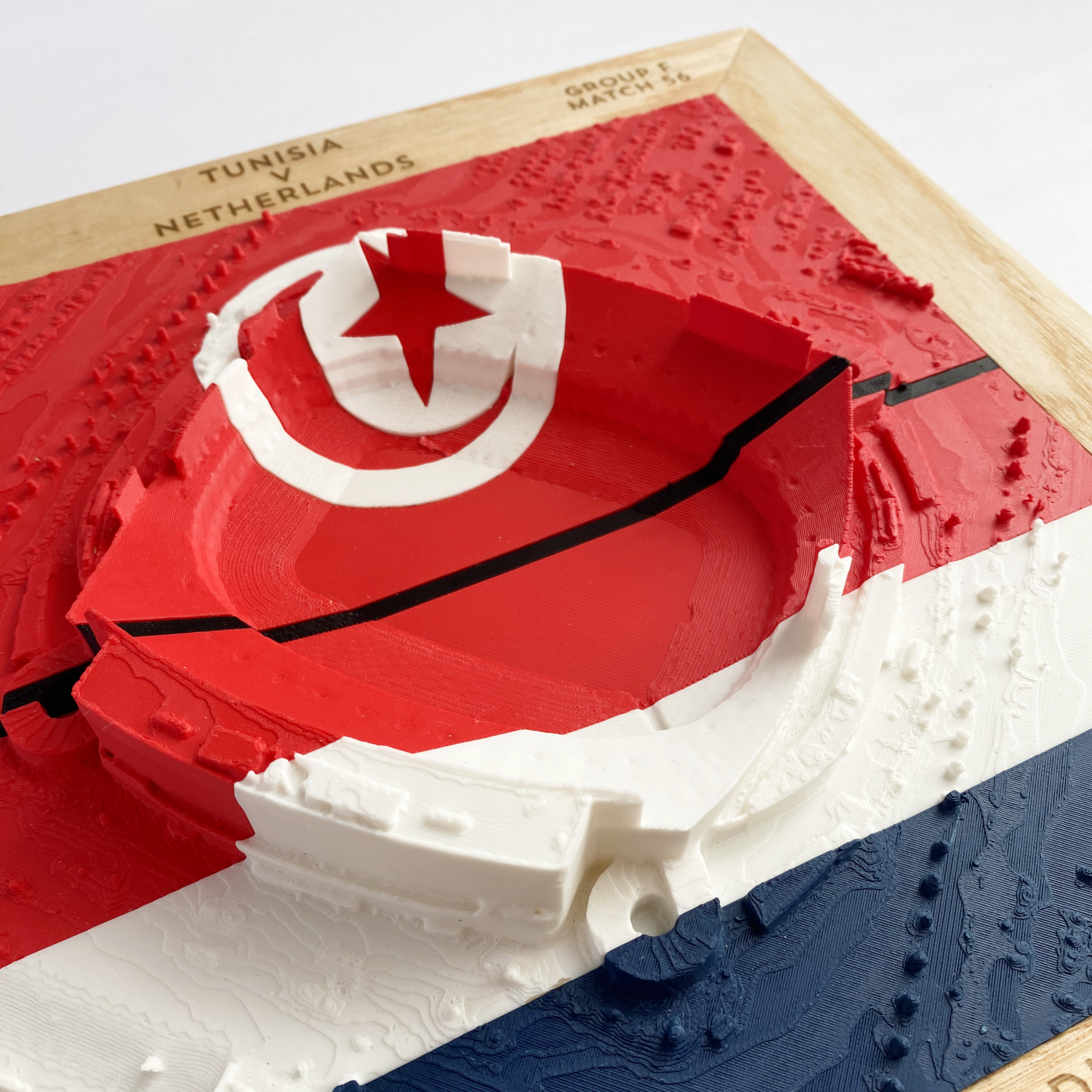 3D printed model of Arrowhead Stadium imprinted with Tunisia's flag on the top half and The Netherland's flag on the bottom half - encased in a solid wooden frame engraved with the text "June 25th 2026; Tunisia v Netherlands; Group F Match 56; Kansas City Stadium, Kansas City, MO, and coordinates"